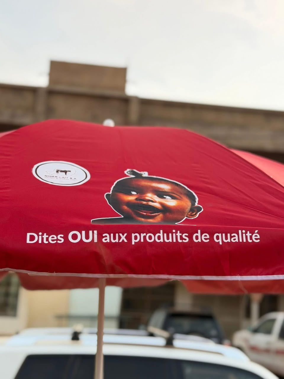 Parasol rouge Niger-Lait portant la signature Dites OUI aux produits de qualité